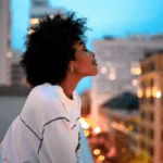 Creative rooftop portrait of a woman overlooking a city at dusk, used by The Bunny Agency for OnlyFans creator branding